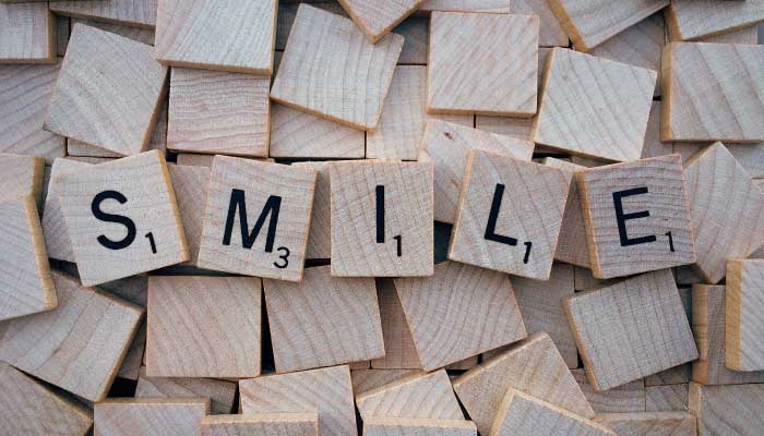 smile spelled with wooden tile letters