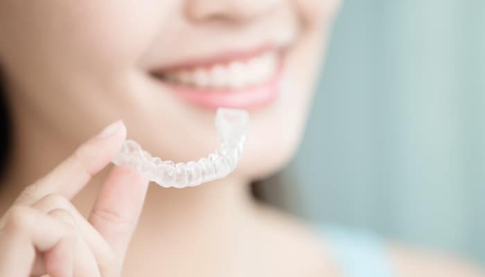 woman holding invisalign clear aligner