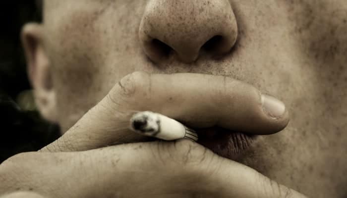 close up of freckled man smoking a cigarette