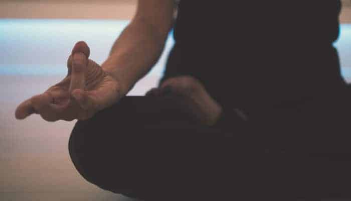 Closeup of a woman sitting cross-legged with her fingers gently pinched together in zen pose of meditation