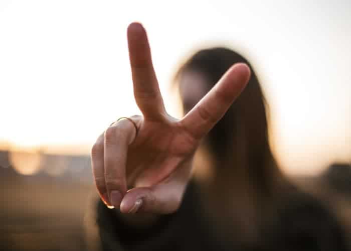 Closeup of a woman holding up 2 fingers to represent biannual dental visits