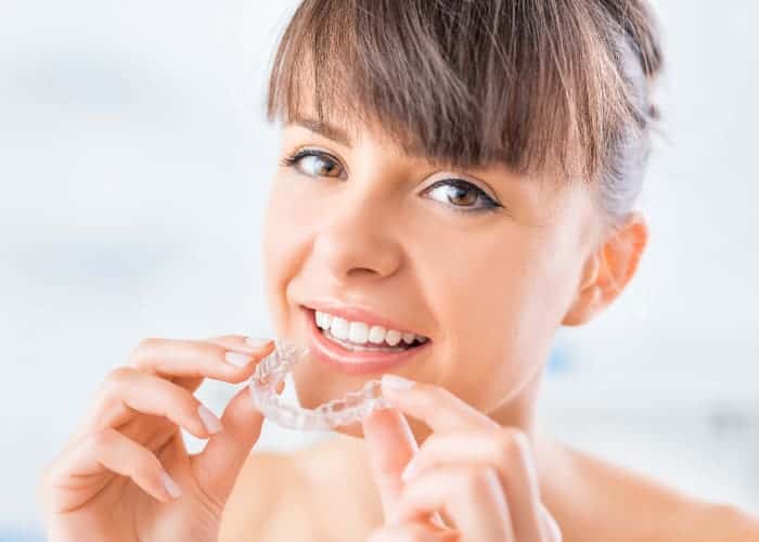 Brunette woman wears clear aligners to discreetly straighten her teeth as an adult