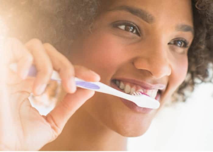 close up of a young woman brushing her teeth