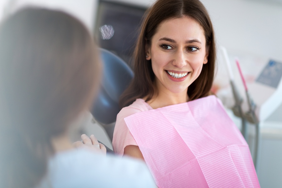 woman in dental chair, guidance on keeping teeth straight after invisalign with retainers