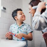 mother brushing teeth with son to prevent cavities in kids
