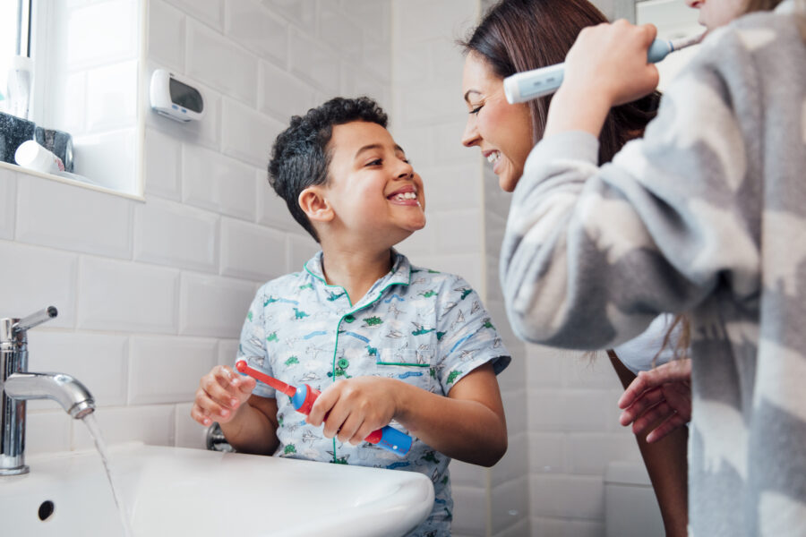 mother brushing teeth with son to prevent cavities in kids
