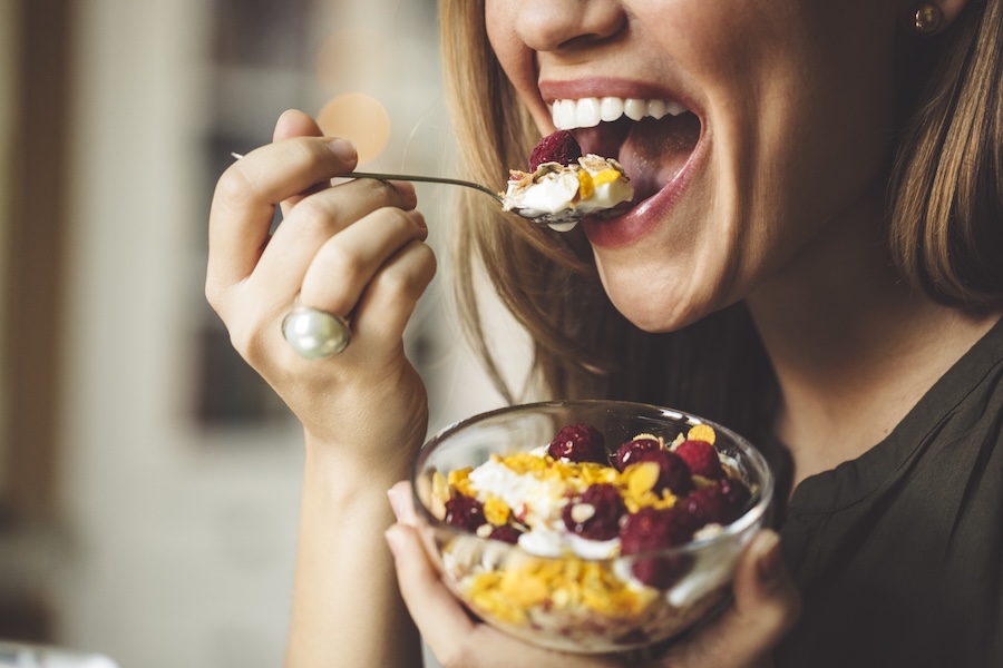woman eating healthy food like yogurts and berries to eat nutrition for healthy enamel and teeth