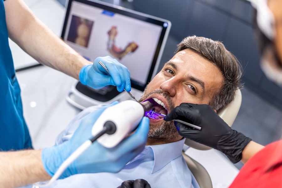 man getting a digital scan of his teeth at the dentist with an itero digital scanner, a kind of modern dental technology